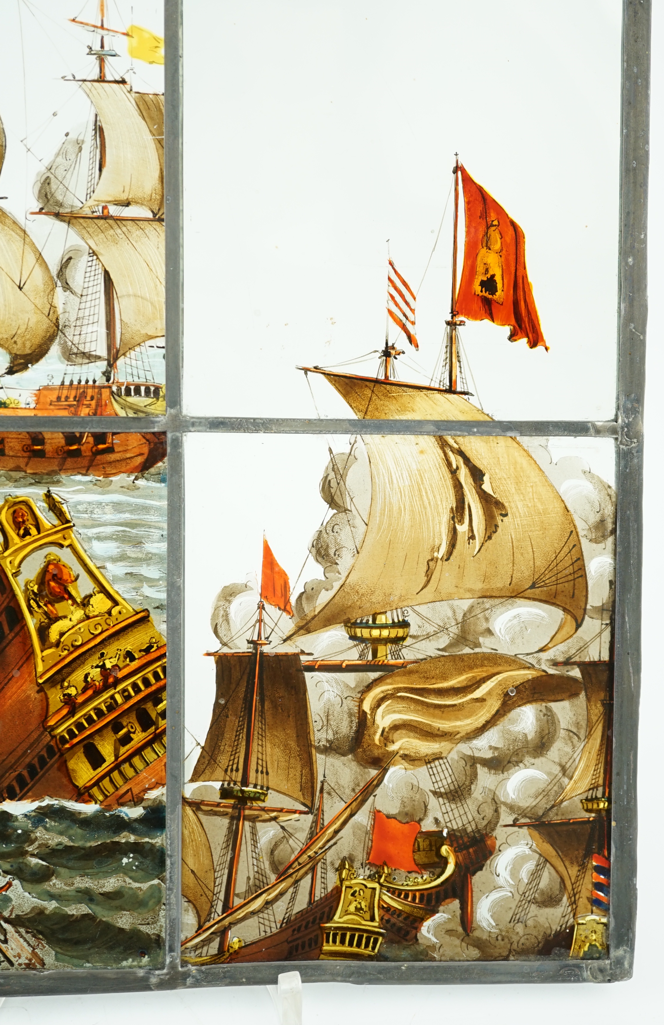 A 18th century Dutch stained glass panel made from four sections depicting a shipwreck and the sails of a fighting galleon, overall 28 x 23cm